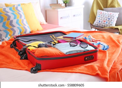 Open suitcase with clothes and personal things packed for travelling