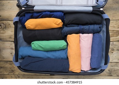 Open suitcase with clothing on wood table