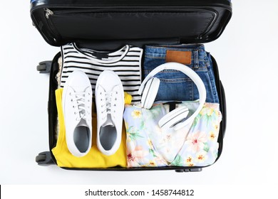 Open Suitcase Fully Packed With Folded Women's Clothing And Accessories On The Floor. Woman Packing For Tropical Vacation Concept. Female Luggage W/ Things. Background, Close Up, Copy Space, Top View.