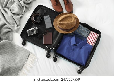 Open suitcase with traveler's belongings on bed, flat lay - Powered by Shutterstock