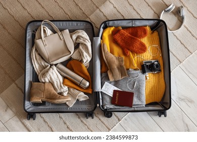 Open suitcase with winter clothes and accessories on carpet, top view - Powered by Shutterstock