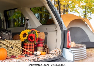 Open Tailgate With Hiking And Picnic Items And Tent In Blurred Background