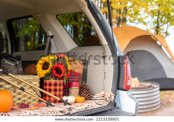 Open tailgate with hiking and picnic items and\
tent in blurred background