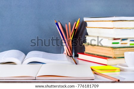 Open textbook and hardback stacked with pencils on the table. The concept of intelligence comes from education. focused on the textbook.