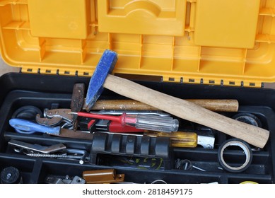 Open toolbox filled with various hand tools including hammer screwdriver and tape high angle view