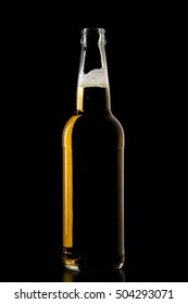 Open transparent beer bottle with foam on a black background