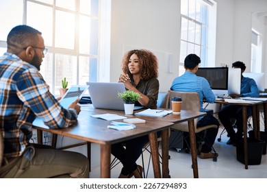 Open and transparent discussions. Shot of two young coworkers having a discussion opposite each other in a modern office.