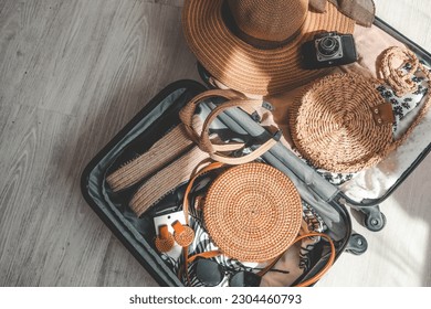 Open travel suitcase with summer accessories on wooden floor. Travel concept. - Powered by Shutterstock