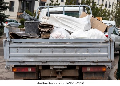 An Open Truck Body Filled With Various Rubbish, Bags, Cardboard, Construction Waste, Rear View. Garbage Collection After Repair And Construction Of Buildings