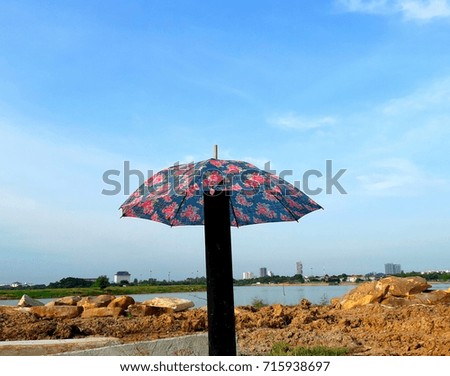 open umbrella in open ground overlooking farway city view