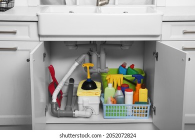 Open Under Sink Cabinet With Different Cleaning Supplies In Kitchen