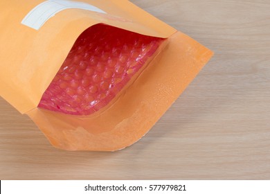 Open used yellow blank envelope with transparent bubble wrap or packaging shockproof on wooden table.