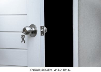 Open white door and silver knob with keys against gray concrete isolated on black background for concept of open the door or close the door and forget the key. - Powered by Shutterstock