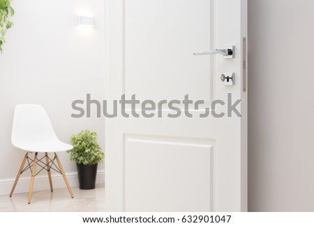 The open white interior doors. Modern chrome handle and lock with key. Wall lamp, chair, and green plant in the background