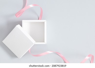 Open white square box mockup with pink ribbon on gray background. Flat lay, top view, copy space - Powered by Shutterstock