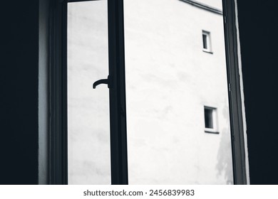 An open window to the inner courtyard, with a view of a house wall.