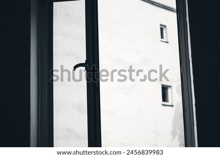 An open window to the inner courtyard, with a view of a house wall.