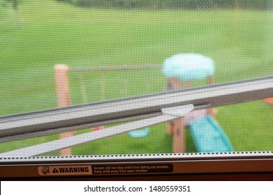 Open window with mesh screen covering and printed child warning.  