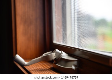 Open window with turn knob on dark wood frame