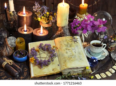 Open witch book with spells, black candles and cup of coffee. Esoteric, wicca and occult background with magic objects, fortune telling and divination ritual, Halloween mystic background. 