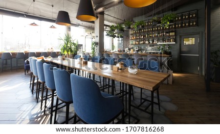Open wooden bar counter with alcohol on shelves in modern cafe, restaurant interior, panorama, copy space