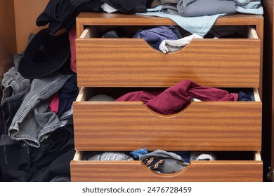 Open wooden dresser with overflowing drawers showcasing a mix of clothing items - a visual representation of daily life disorganization and the need for a tidier storage solution. Home Organization