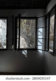 Open wooden windows framing dramatic limestone cliffs, creating a peaceful mountain retreat and nature escape
