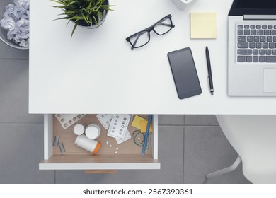 Open work desk drawer containing many different medicines and drugs: healthcare and addiction concept, copy space