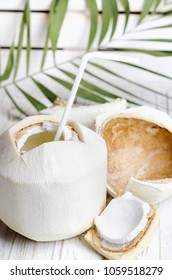 Open young coconut on white wooden background.