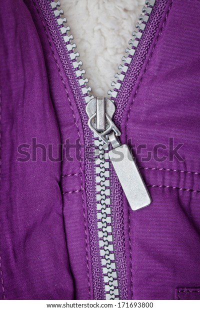 An open zip on\
the front of a purple jacket