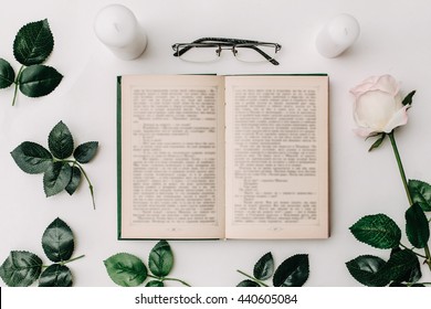 Opened Book, Glasses, Pink Rose On White Background. Flat Lay