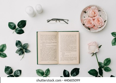 Opened Book, Glasses, Pink Roses On White Background. Flat Lay