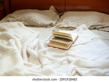 Opened Book On A Cozy White Knit Mohair Blanket On A Bed 