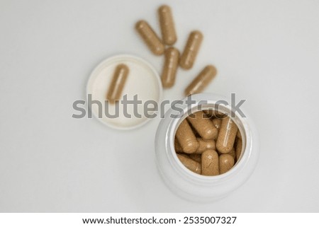Opened bottle is laying on its side with brown pills spilling out of it