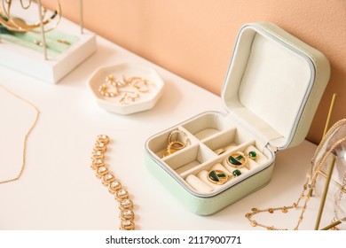 Opened box and stylish jewelry white table near color wall