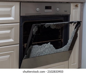 Opened Broken Oven Door In The Kitchen, Side View, Close-up. Broken Glass From Overheating. Warranty Repair