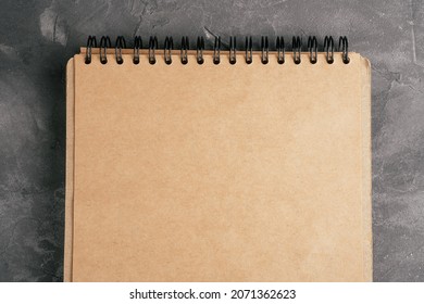 Opened Brown Kraft Paper Notebook On Spring On Gray Concrete Surface. Top View. Copy Space