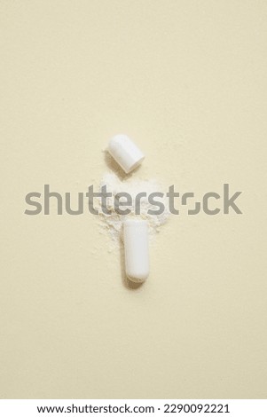 opened capsule showing supplement powder on beige colour background