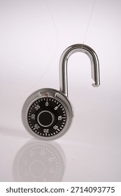Opened combination padlock with dial showing zero, chrome and black, on white background