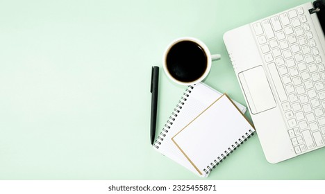 Opened computer on the table, white cup of coffee, notepad and pen, office supplies.  Flat lay on green background, office work concept, back to school, webinars, online learning. Top view. - Powered by Shutterstock