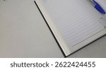 Opened diary on white table and a pen