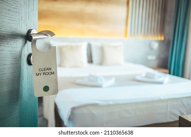 Opened door of hotel room. Door of hotel room with please make up room sign. Hotel room or apartment doorway with key and keyring key fob in open door and bedroom in background - Powered by Shutterstock