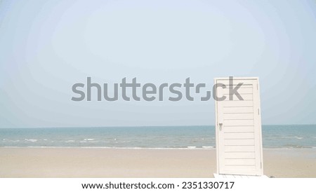 opened door with key in lock in beach,White wooden door at the beach with blue sky and sea background.
