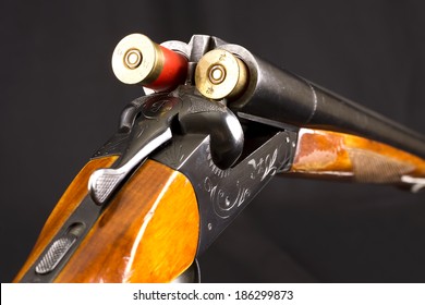 Opened double-barreled hunting gun with two cartridges against black