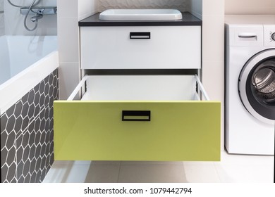 Opened Drawer In A Bright And Colorful Bathroom Furniture. Clever Solution For Storage. White And Lime Glossy Mdf Fronts With Black Handle For Contrast With Black Countertop. 