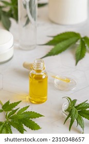 Opened Dropper bottle with pipette near green cannabis sativa leaves on a marble table close up. Organic skincare beauty product. Eco friendly CBD oil - Shutterstock ID 2310348657