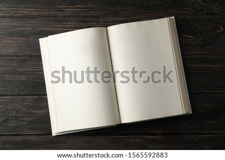 Opened empty book on wooden background, space for text