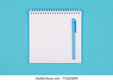Opened empty white notepad on blue background. Shot from top point of view with copy space