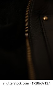 Opened gold zipper on a black leather bag
