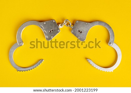 Opened handcuffs on yellow background. Release from prison, freedom concept. Imprisonment, deprivation of liberty and apprehend perpetrators.
